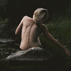 half naked woman sitting on rock